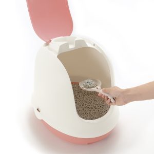 human hand scoops kitty litter from hooded litter box